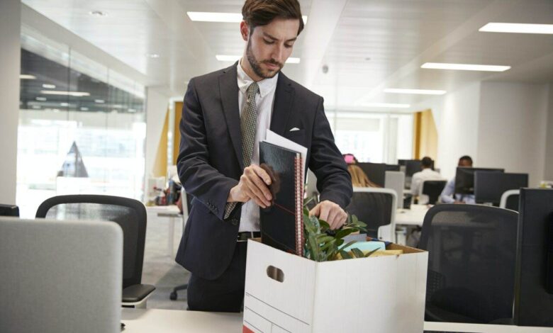 Fired male employee packing box of belongings in an office