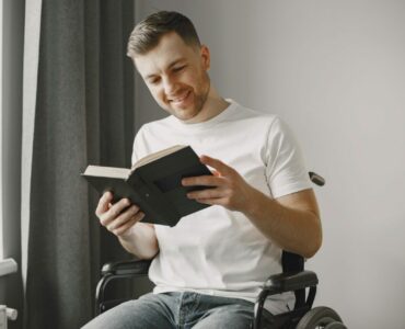 Handicapped man in wheelchair reading a book at home