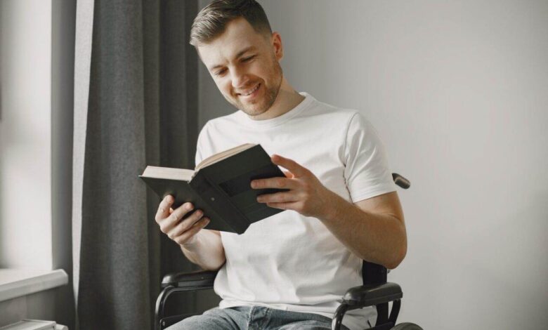 Handicapped man in wheelchair reading a book at home