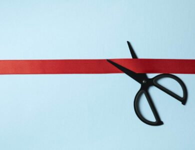 Black scissors and red ribbon on blue background