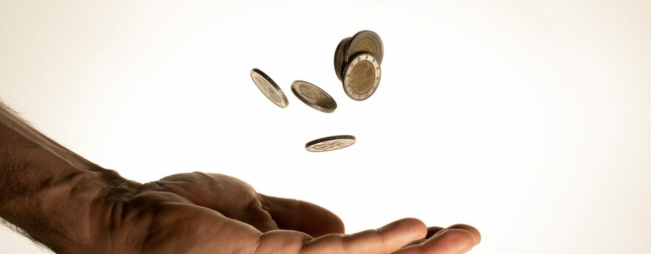 Flying money coins in the man's hand