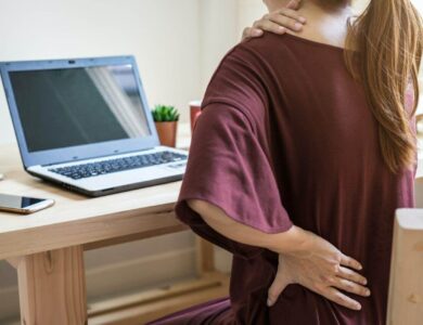 Young woman working at home and having back pain