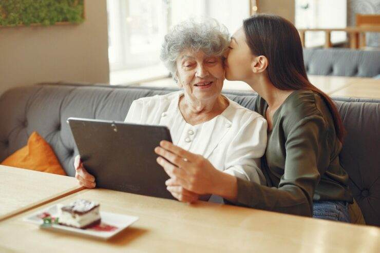 Girl teaching her grandmother how to use a tablet