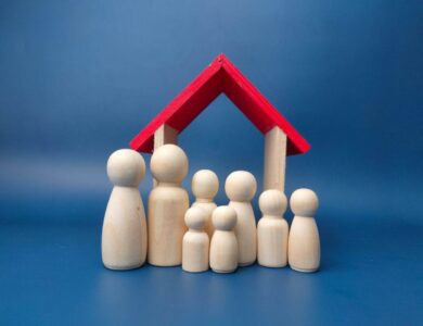A family wooden doll with wooden house on a blue background.